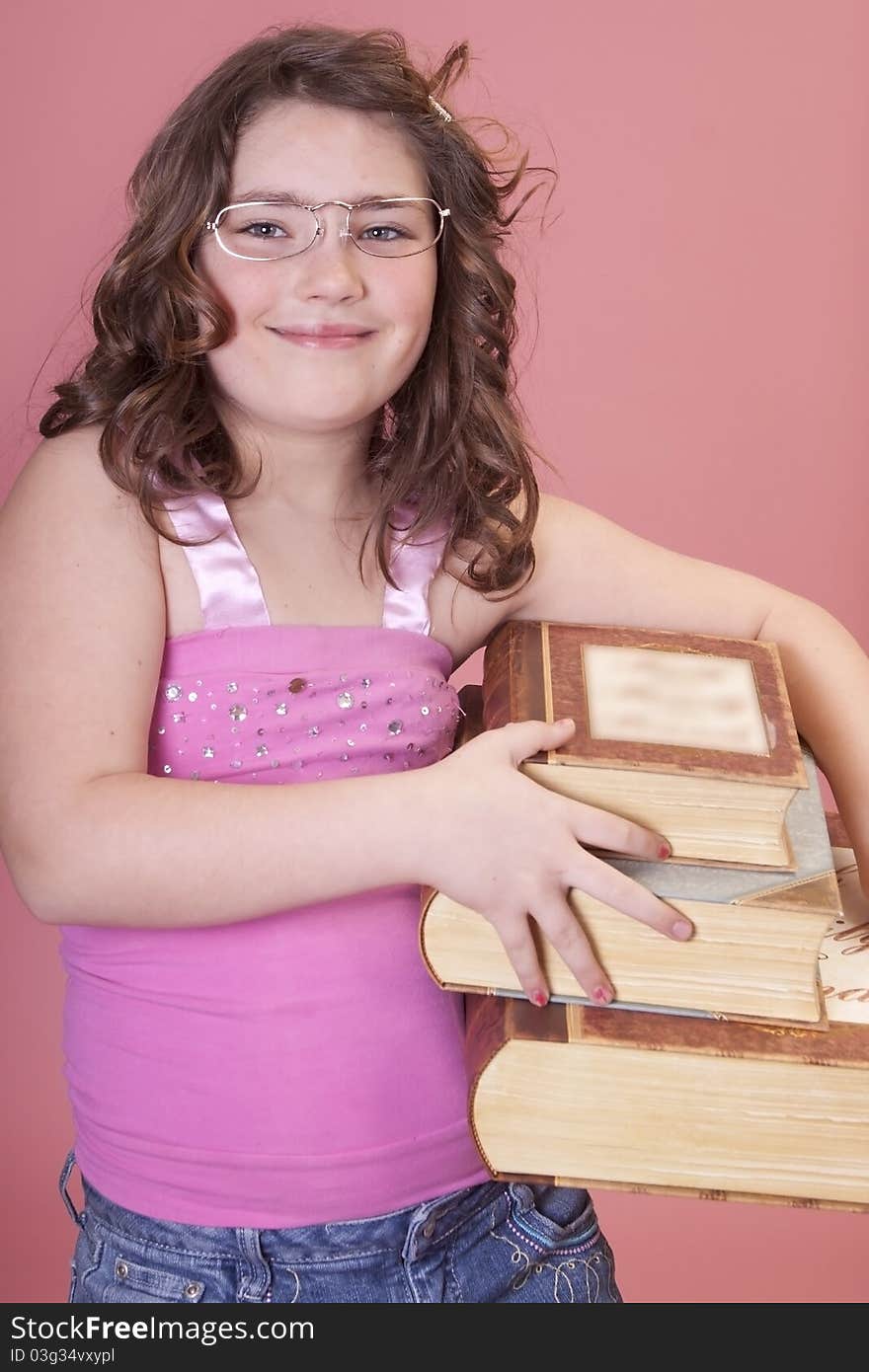 Young school aged girl wearing glasses and carrying lots of books. Young school aged girl wearing glasses and carrying lots of books.