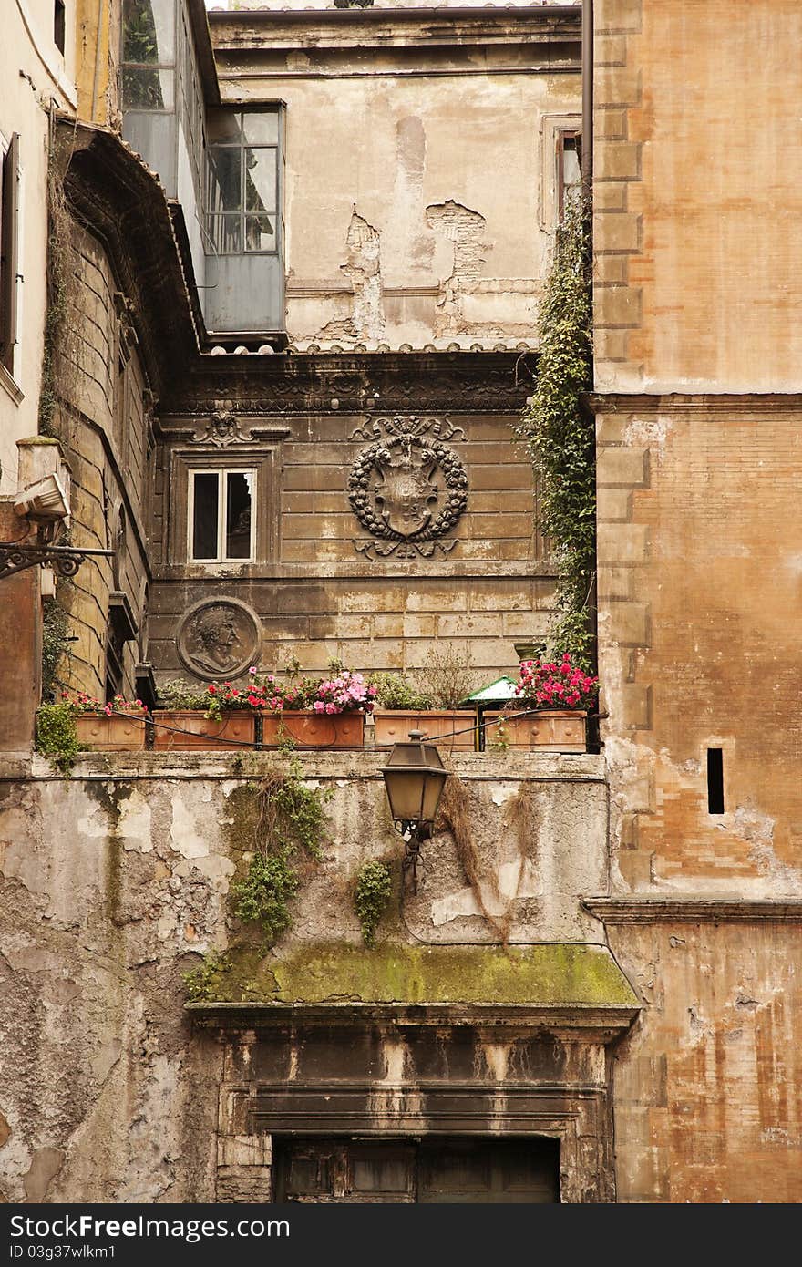 A weathered multi-story apartment building in a Tuscan style is seen with Roman reliefs on the second story. Vertical shot. A weathered multi-story apartment building in a Tuscan style is seen with Roman reliefs on the second story. Vertical shot.