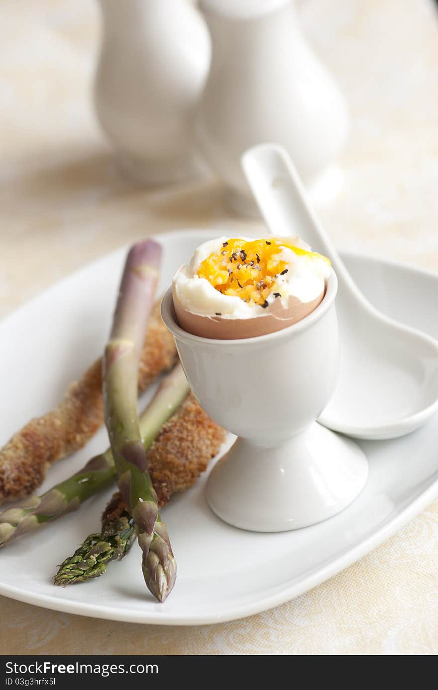 Soft boiled egg with asparagus soldiers on a plate