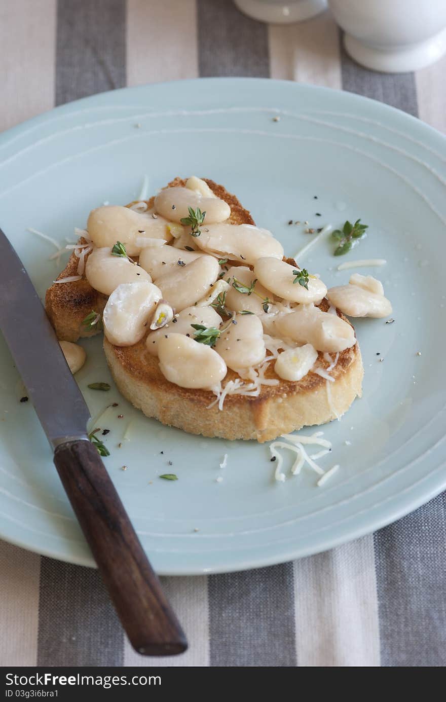 Toasted bread topped with butterbeans and thyme on a plate