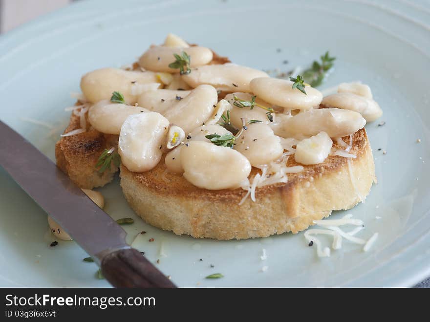 Toasted bread topped with butterbeans and thyme on a plate