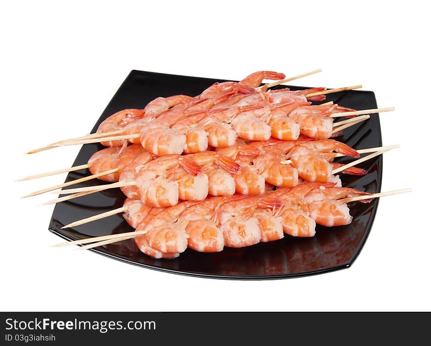 Skewers of shrimp on a black plate, isolated on a white background