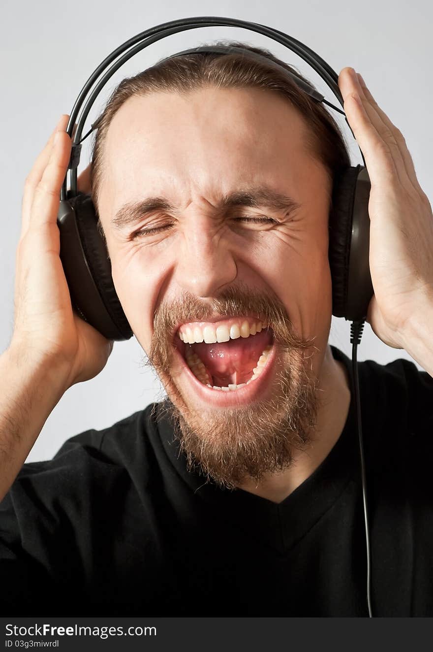 Young man in headphones and screaming loudly. Young man in headphones and screaming loudly