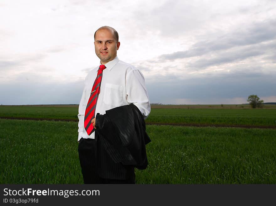 Young business the person with the big smile upon the face costs among an open country and the sky in the weakened condition. Young business the person with the big smile upon the face costs among an open country and the sky in the weakened condition