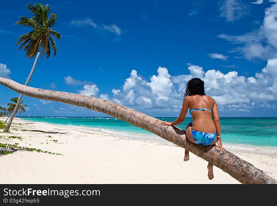 Tanned Woman Sitting On A Palm White Sand Beach