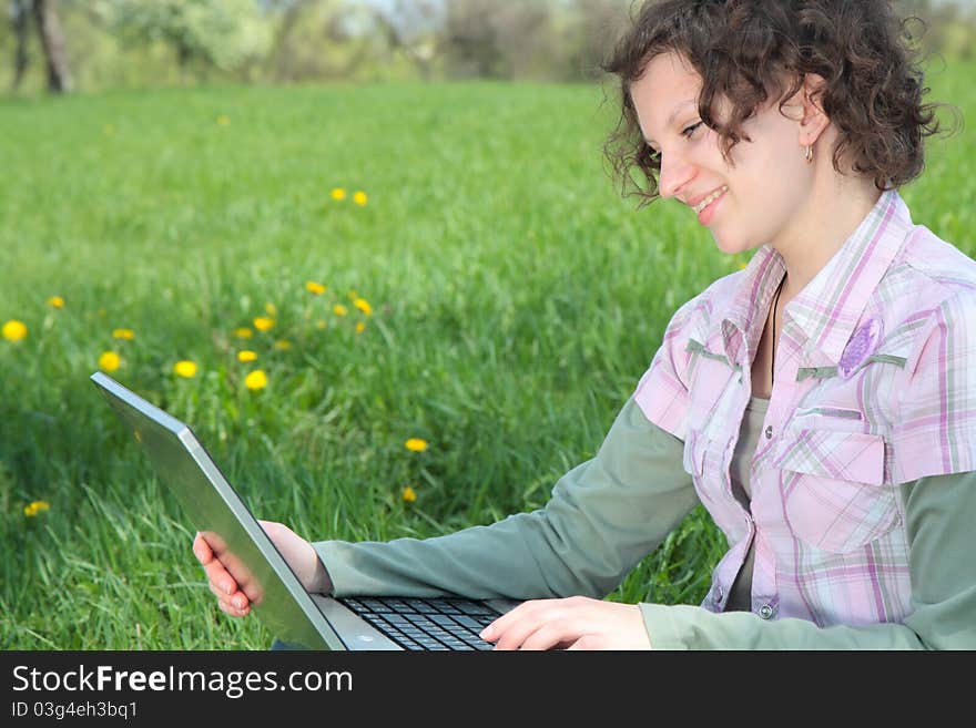 Girl with  laptop on the spring meadow