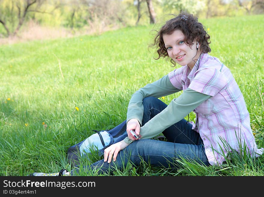 A young attractive girl listening to music in the park