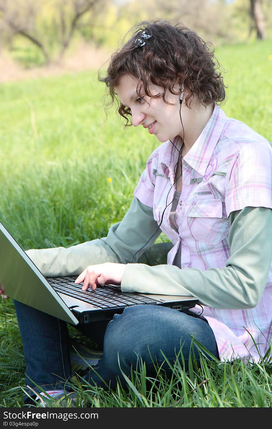 Girl with  laptop on the spring meadow