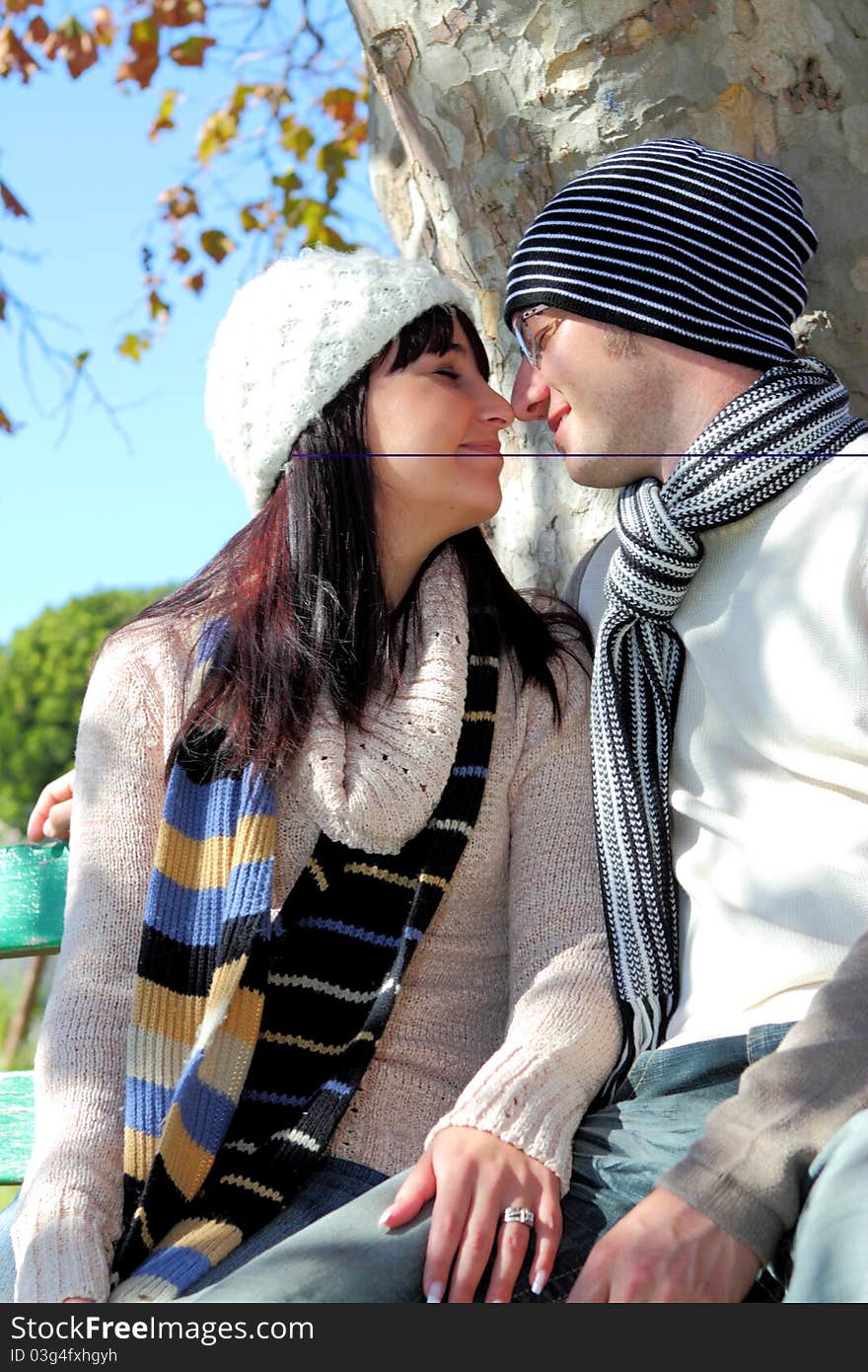 Young couple looking at each other on a park bench in winter clothes