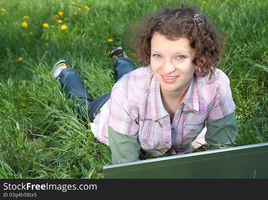 Girl with a laptop on the spring meadow