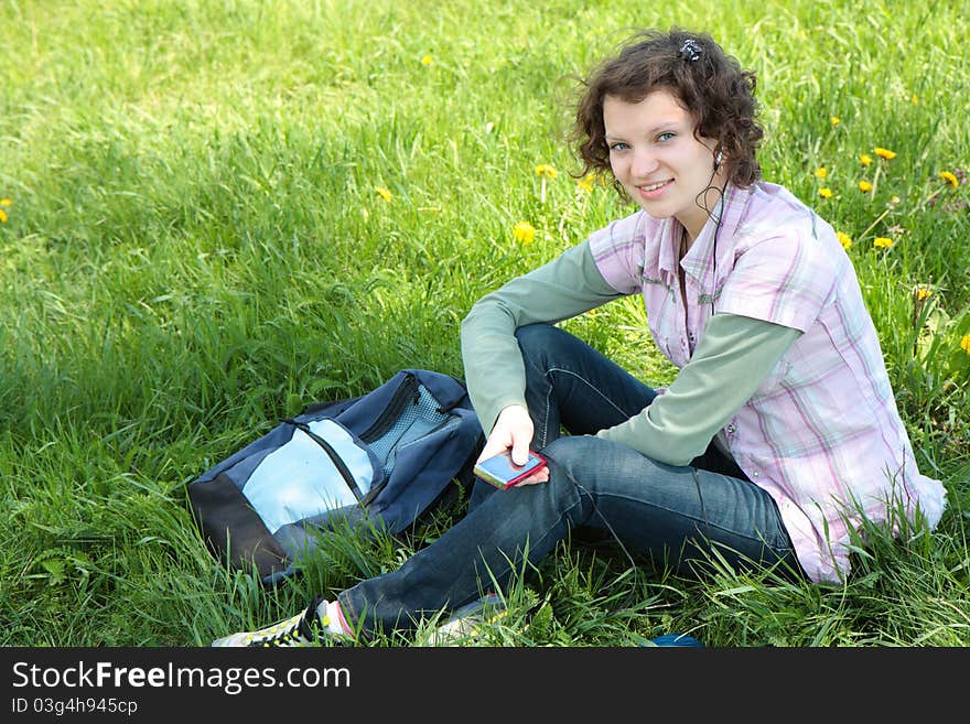 A young attractive girl listening to music in the park