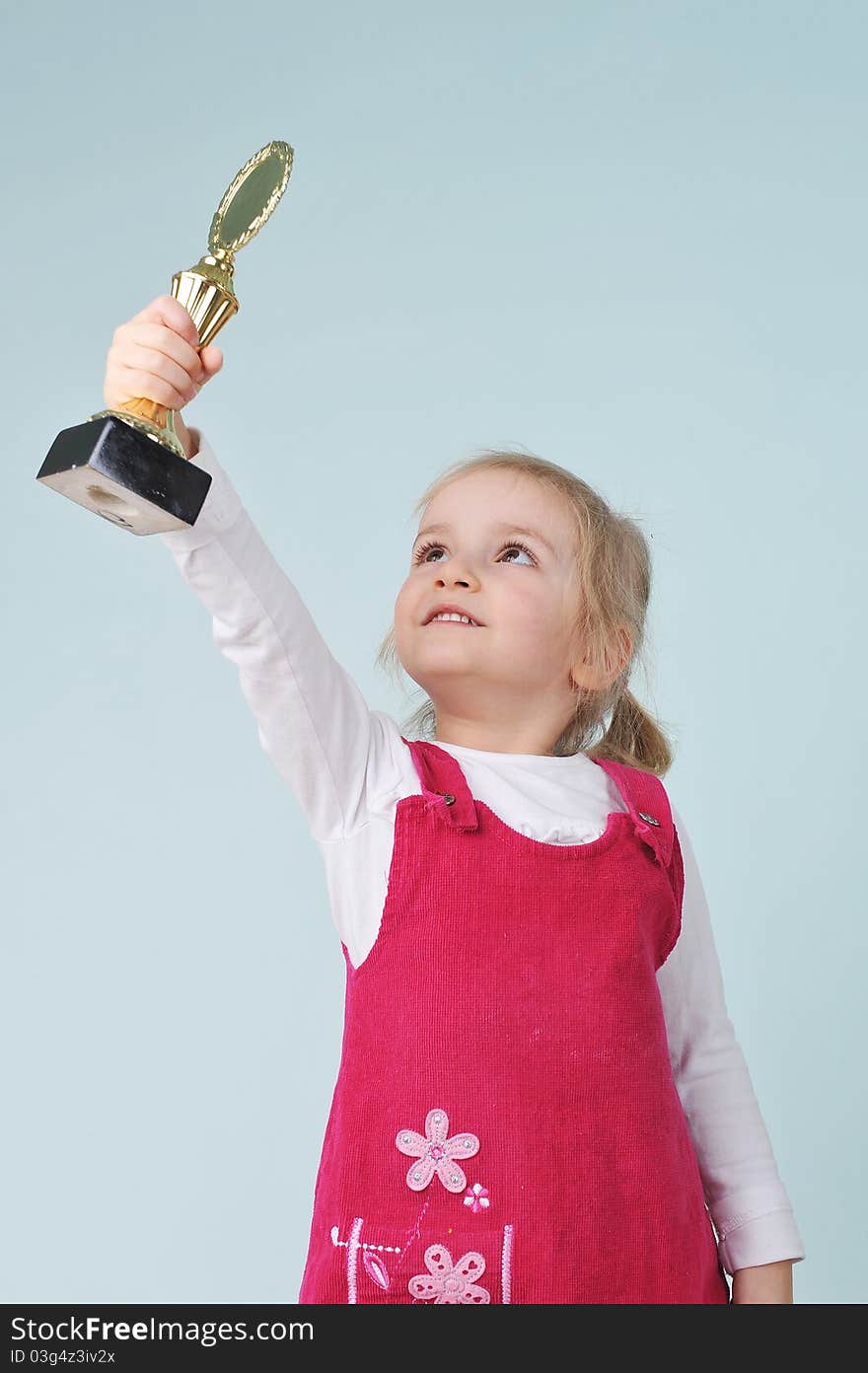 Lovely blond little girl with champion cup