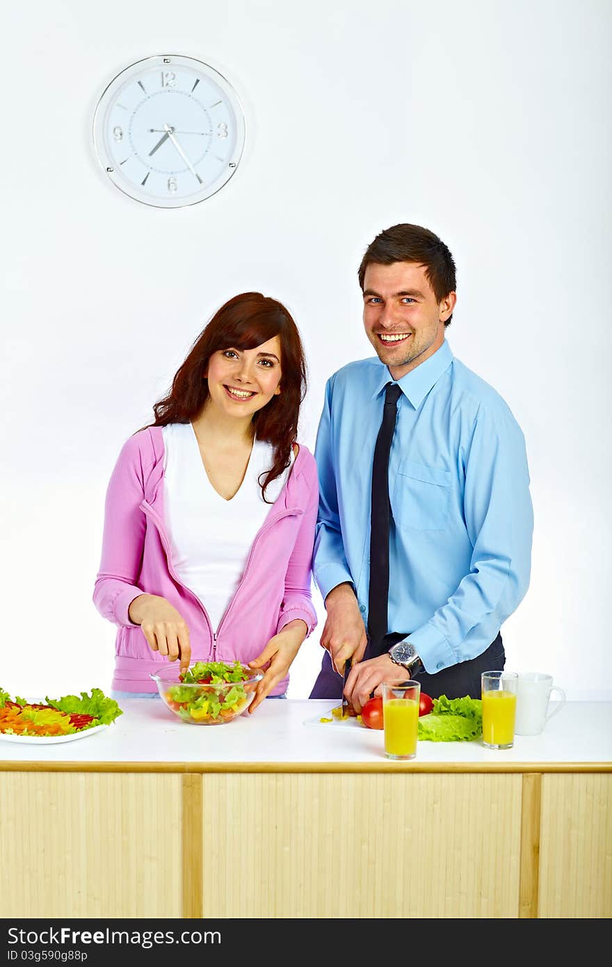 Beautiful couple preparing a salad for lunch in the kitchen