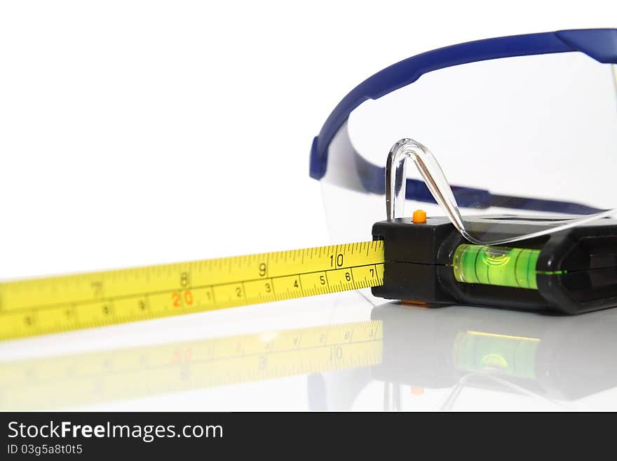 Safety gear, measuring tape and goggles safety - over a white background. Safety gear, measuring tape and goggles safety - over a white background