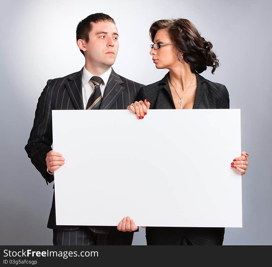 Young couple presenting a blank board over white background. Young couple presenting a blank board over white background