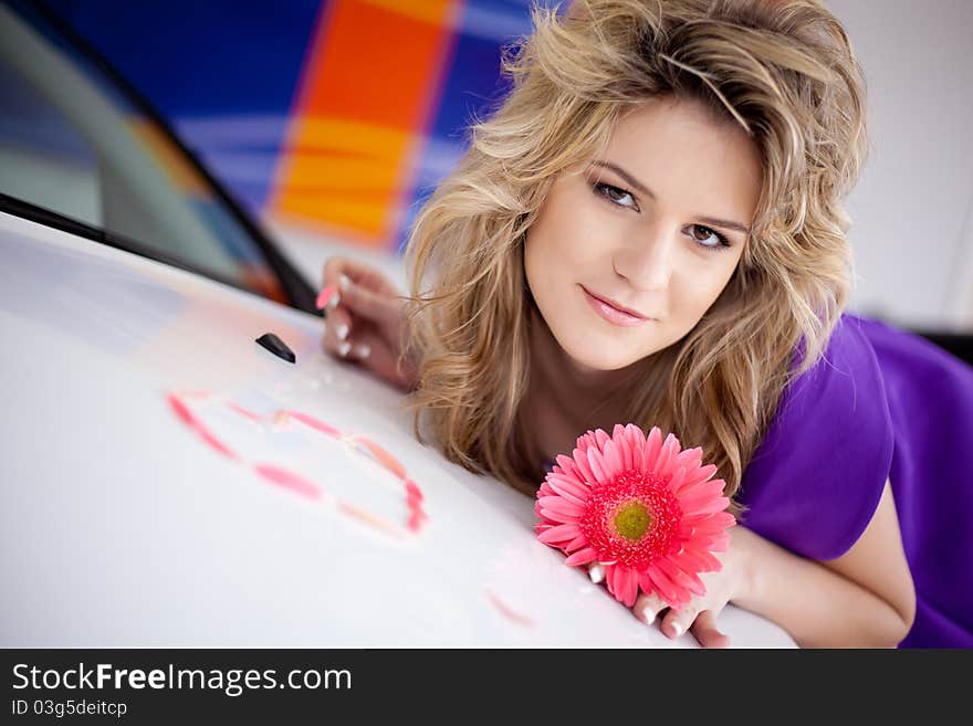 Young woman on hood of New car with flower and pet