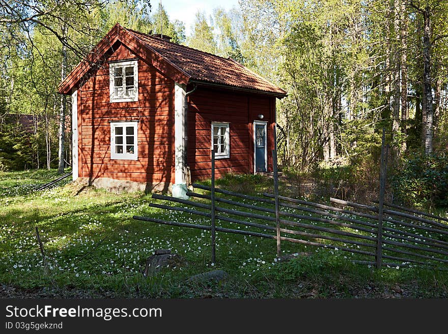 Idyllic Swedish house in a forest with old fence. Typical old wooden, painted red and white. Idyllic Swedish house in a forest with old fence. Typical old wooden, painted red and white.