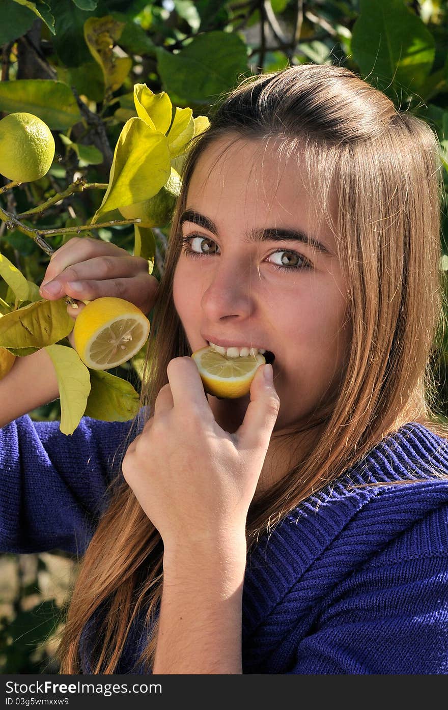 Girl eating a lemon from the tree