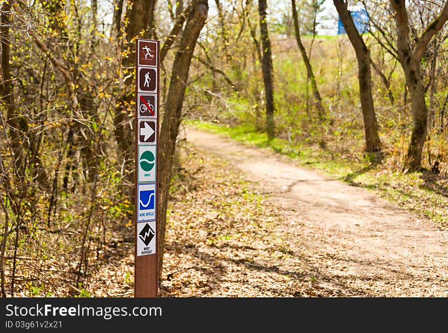 A Biking, Walking, and Hiking sign at the start of a Trail in the woods. A Biking, Walking, and Hiking sign at the start of a Trail in the woods