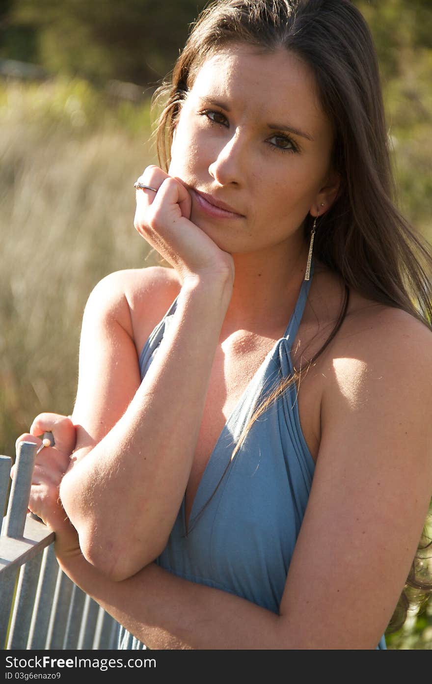 A young woman in a blue dress posing and looking at the camera. A young woman in a blue dress posing and looking at the camera.