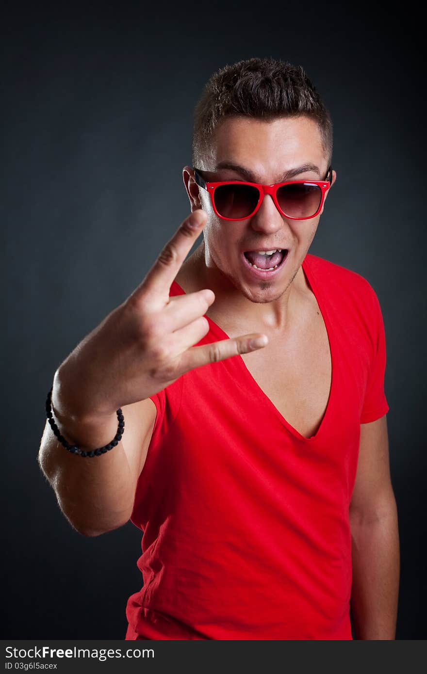 Fashion man making a rock sign on dark background