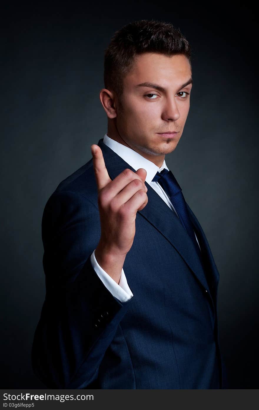 Portrait of handsome stylish man in elegant suit pointing the finger