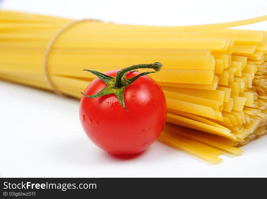 Raw yellow pasta and a red tomato. Raw yellow pasta and a red tomato