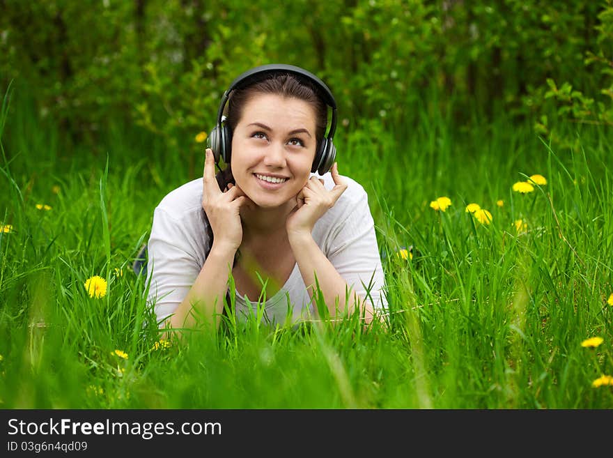 Girl with headphones lying in the grass