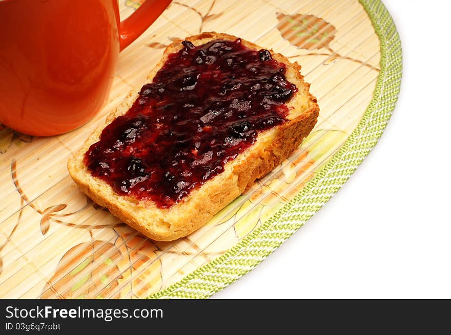 Slice of bread with jelly on placemat on white background