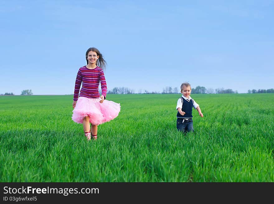 A beautiful sister runing with her cute little brather on the grass. A beautiful sister runing with her cute little brather on the grass