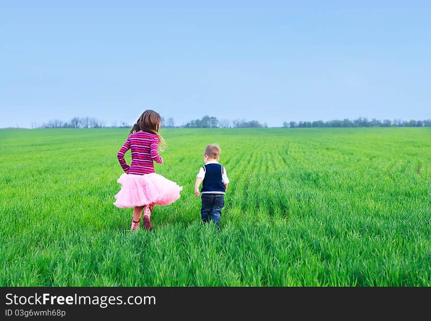 A beautiful sister runing with her cute little brather on the grass. A beautiful sister runing with her cute little brather on the grass