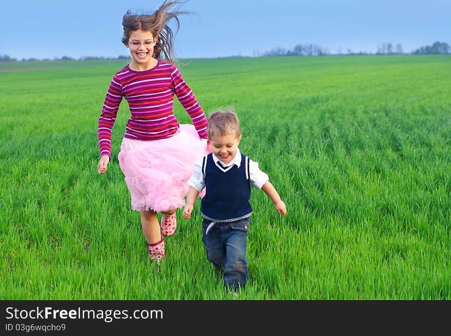 Sister runing with her brather on the grass