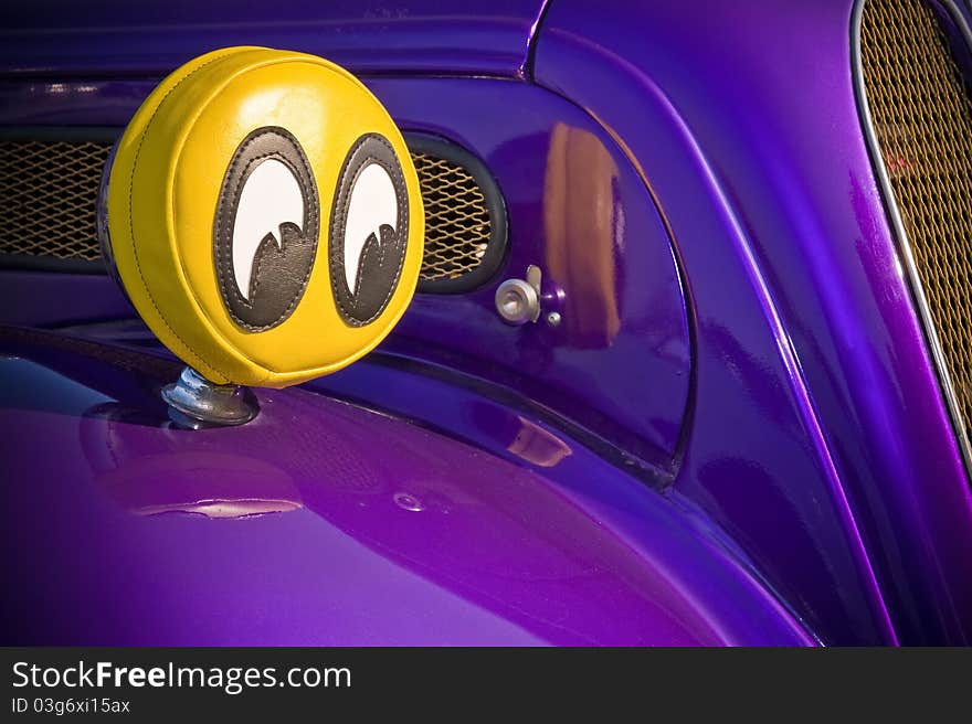 Humorous big eyes covering the headlights of a purple car