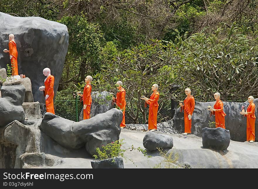 Figures of monakhs in orange dress stay on stone road. Figures of monakhs in orange dress stay on stone road