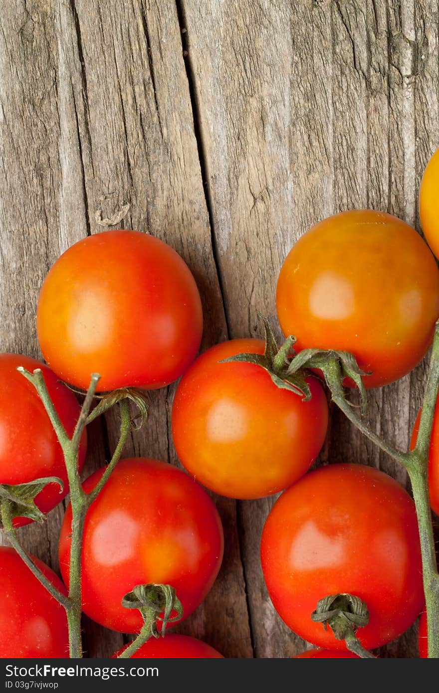 Branch of fresh cherry tomato on wooden background