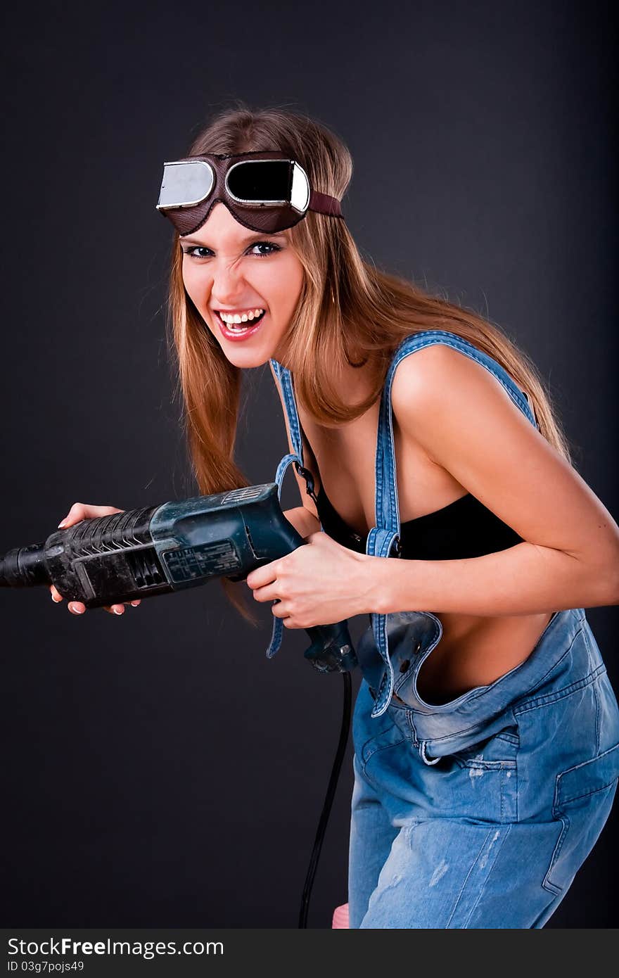 Girl with a drill in building overalls