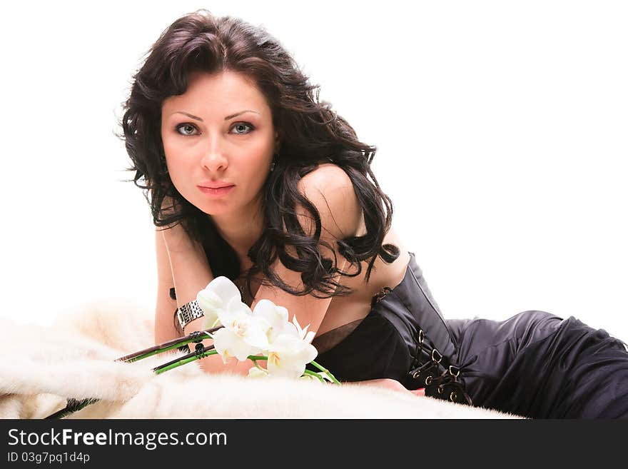 Young beautiful woman with flower lies on fur coat on a white background