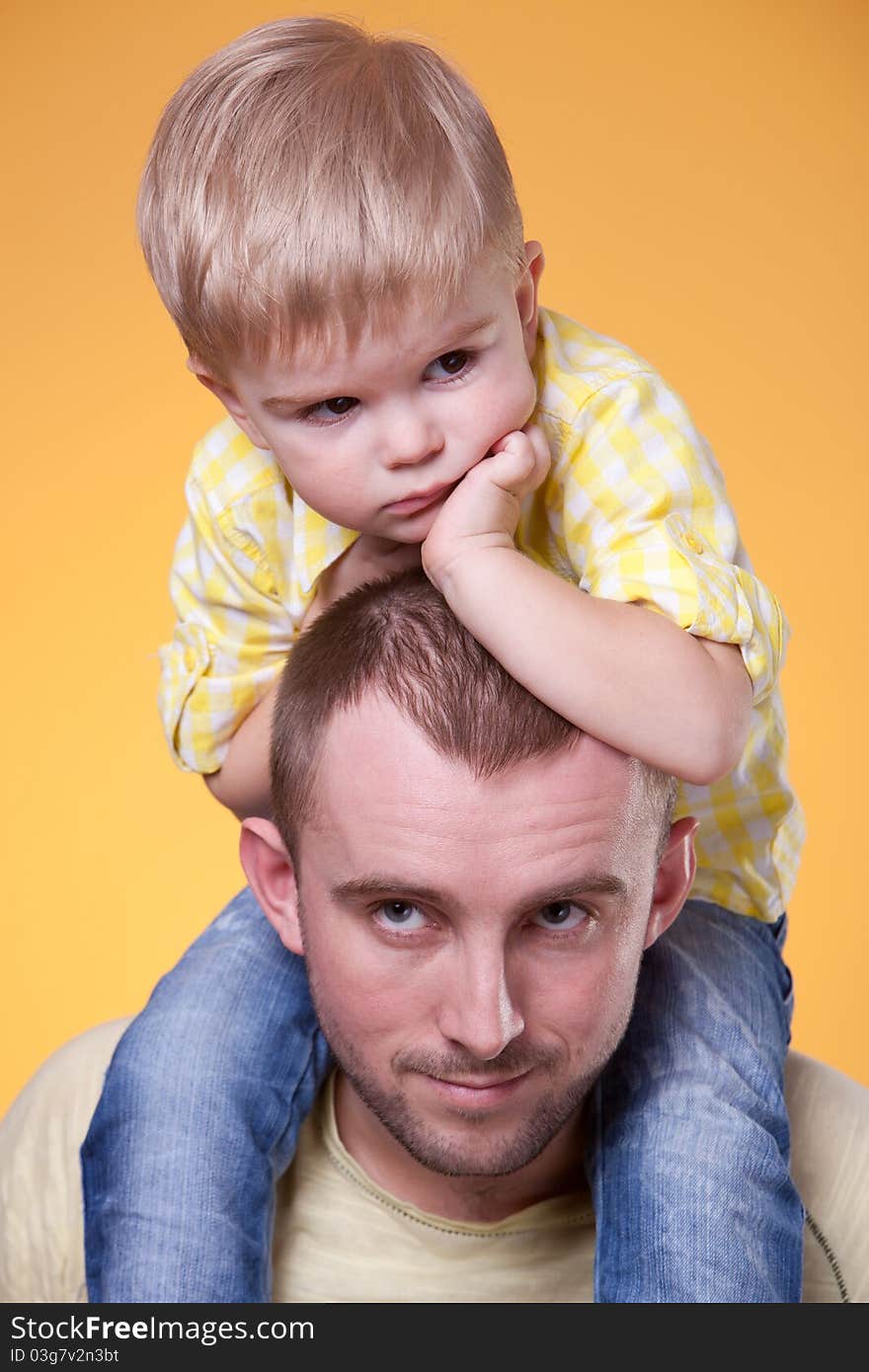 Young father with little thoughtful son on his shoulders. Young father with little thoughtful son on his shoulders