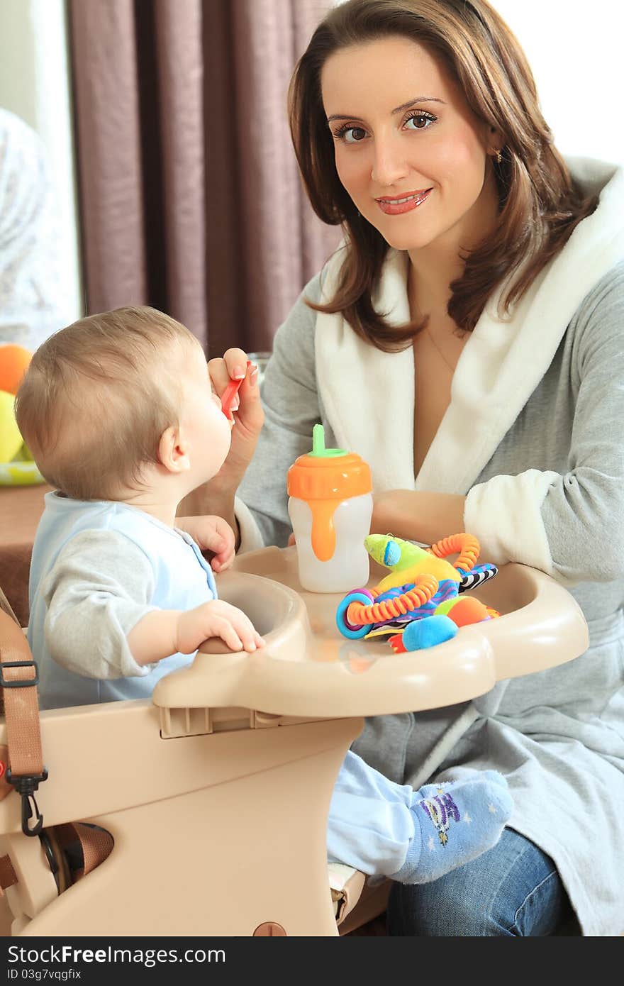 A mother is feeding her baby in the highchair at home. A mother is feeding her baby in the highchair at home.