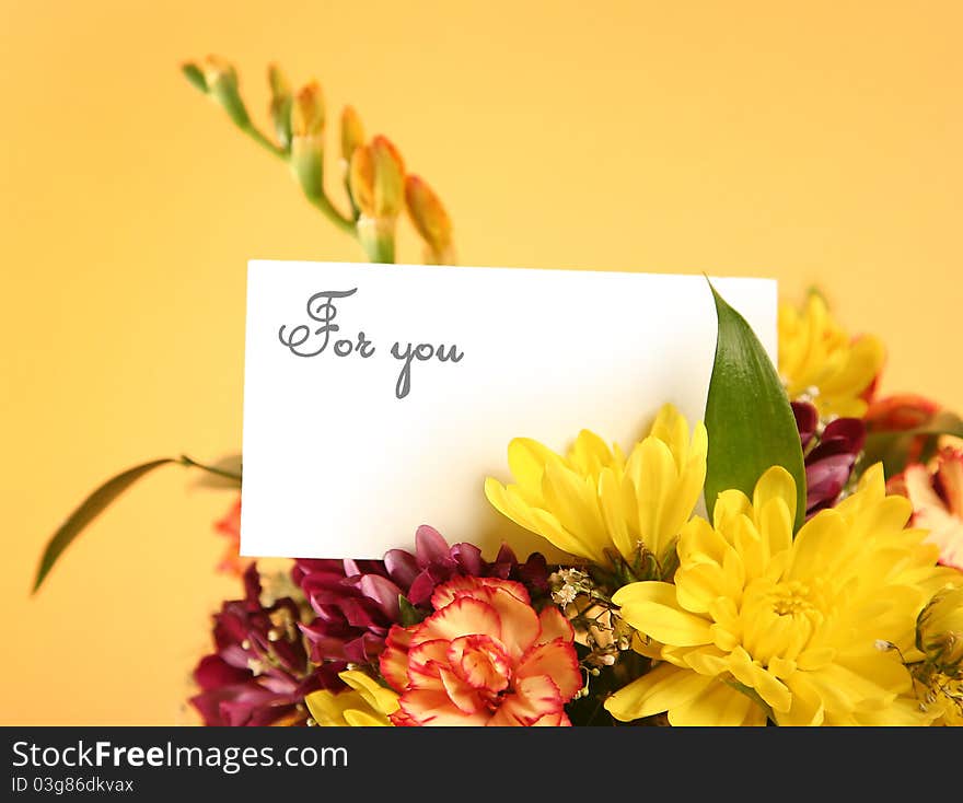 Bright flowers with card on yellow