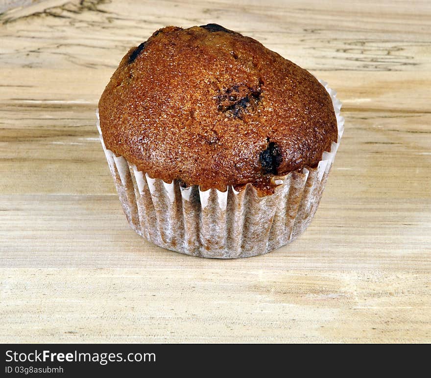 A Muffin on a wooden surface. Photographed in a studio.