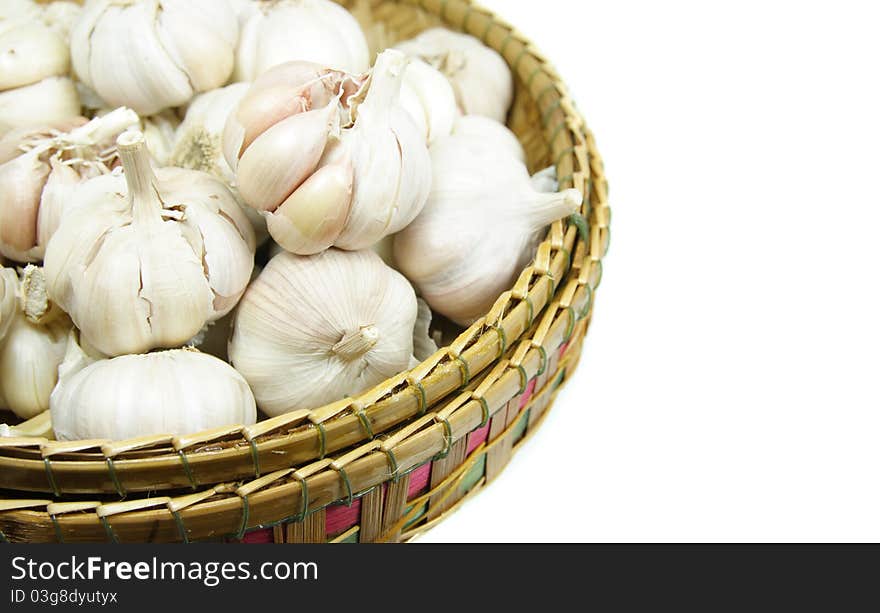 Garlic bulbs in a wicker basket on white