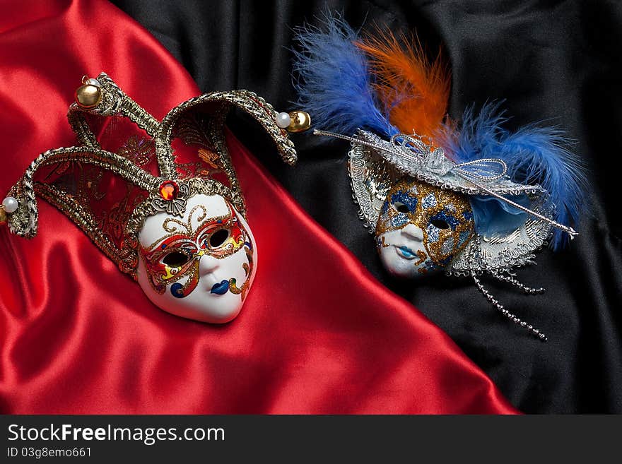 Two venetian mask on a black and red silk