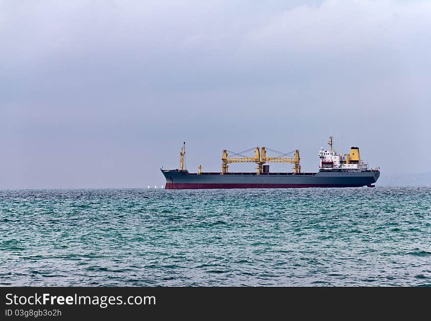 Cargo ship leaving port on a cloudy day. Cargo ship leaving port on a cloudy day