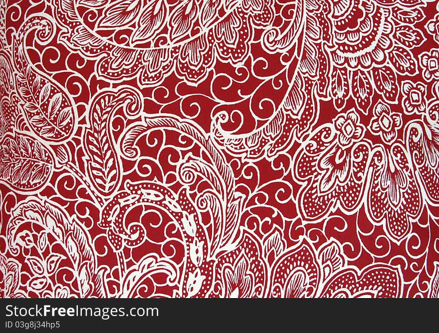 Red fabric with a printed white floral/paisley pattern