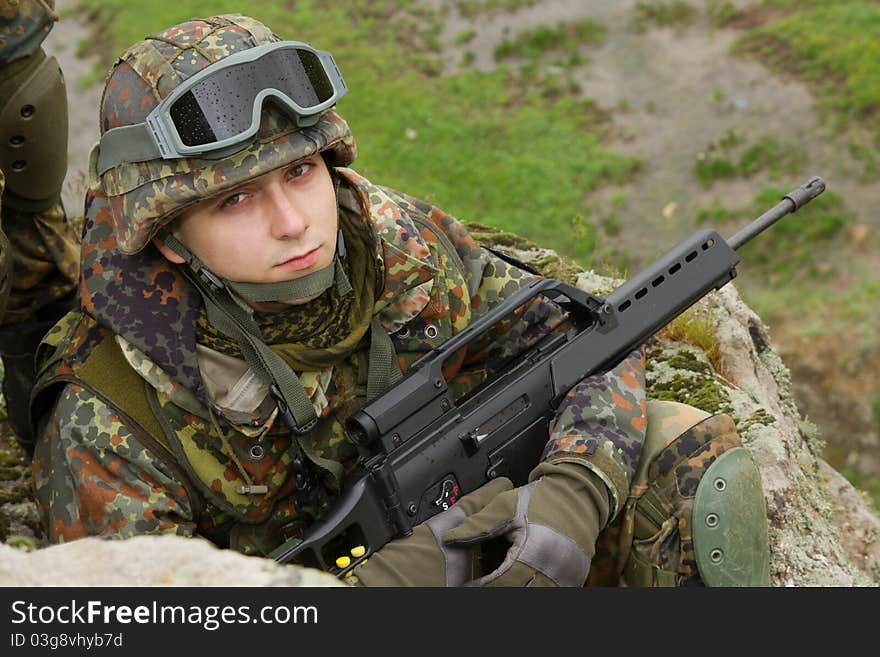 Portrait of young soldier sitting with a rifle