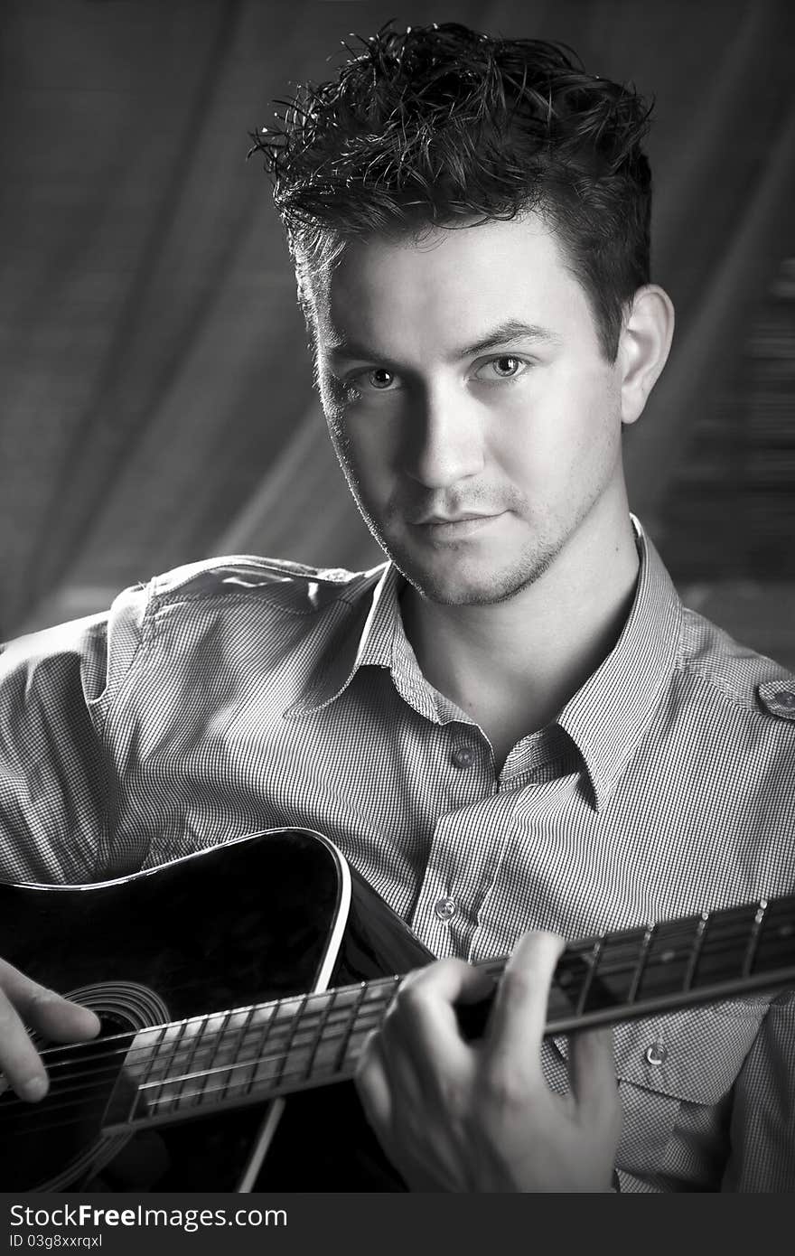 Classy romantic guy sitting on a chair with a guitar in his hands. Black and white photography. Classy romantic guy sitting on a chair with a guitar in his hands. Black and white photography.