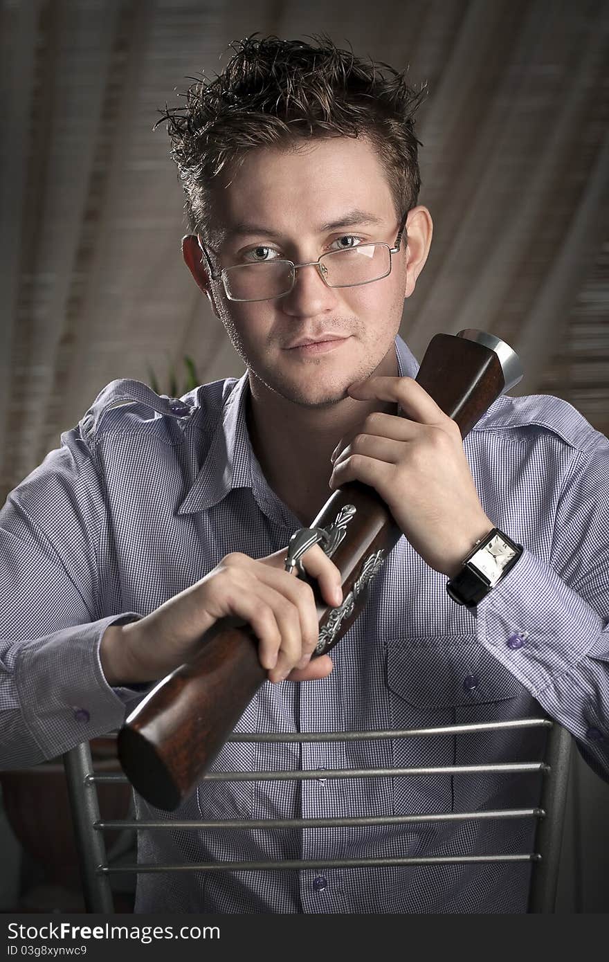 Classy romantic guy with glasses sitting on a chair with musket in his hands. Classy romantic guy with glasses sitting on a chair with musket in his hands.