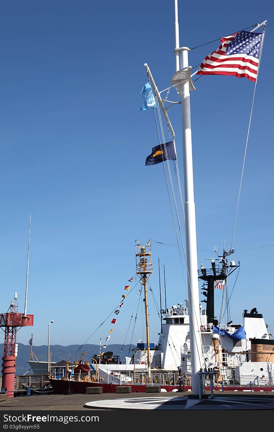 A coast guard ship docked and a mast with flags at the maritime museum in Astoria Oregon. A coast guard ship docked and a mast with flags at the maritime museum in Astoria Oregon.