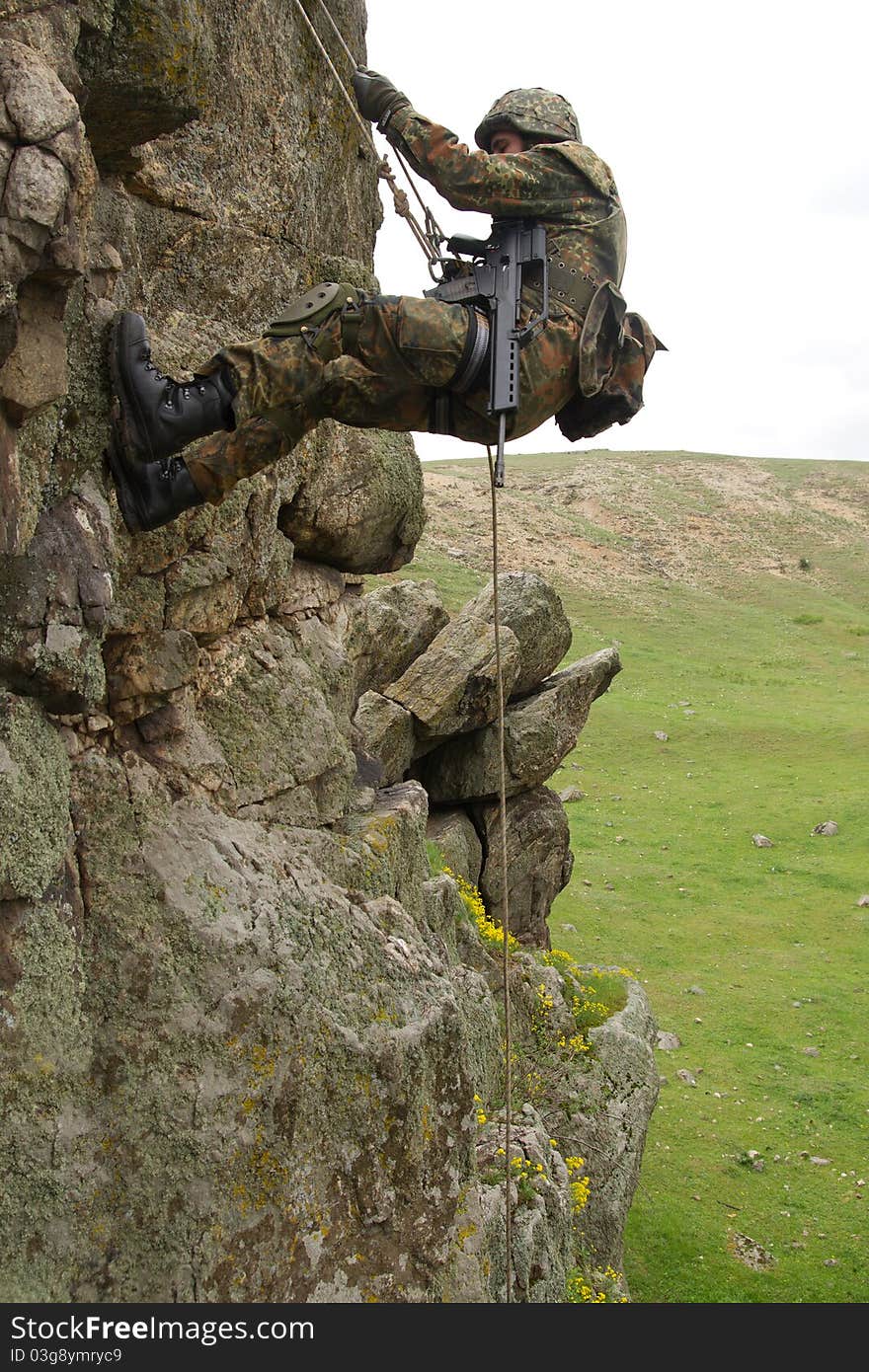 Armed military alpinist climbing